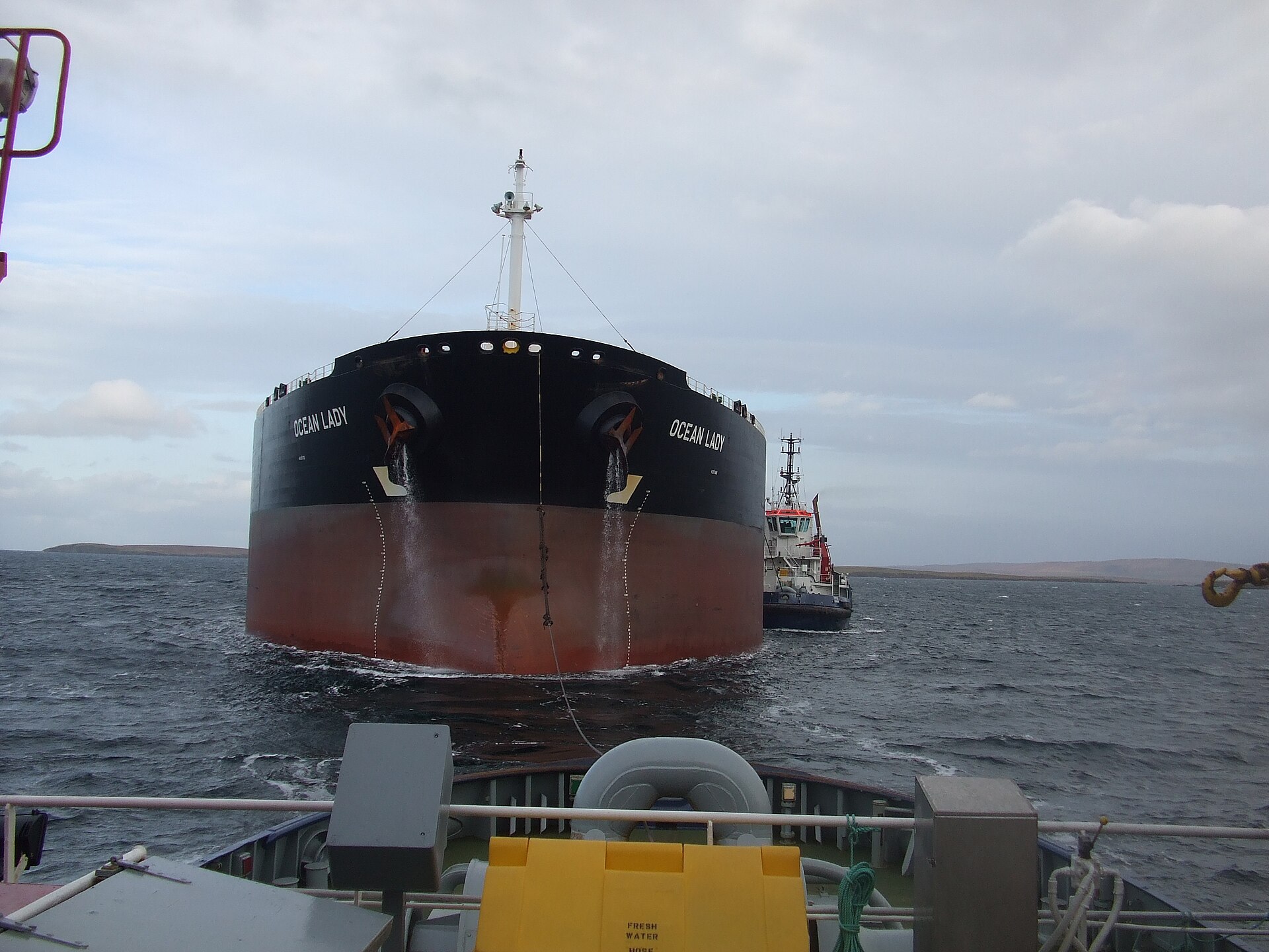 An oil tanker escorted by tugboats into a terminal